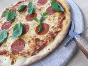 a pizza on a plate with a pizza cutter at Oxgang Kitchen Bar & Rooms in Grangemouth