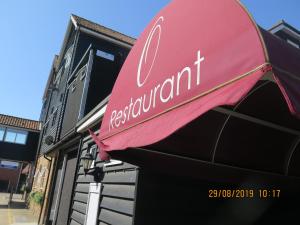 een rood restaurantbord aan de zijkant van een gebouw bij Oyster Fleet Hotel in Canvey Island