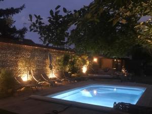 uma piscina à noite com cadeiras e uma parede de tijolos em La Paresse en Ville em Bayeux