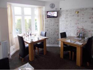 a dining room with two wooden tables and chairs at Penarth Guest House in Par