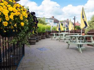 a row of picnic tables with yellow flowers and umbrellas at The Olde Peculiar in Rugeley