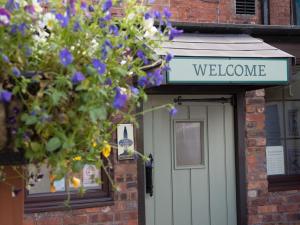 un cartello di benvenuto sopra una porta con fiori viola di The Olde Peculiar a Rugeley