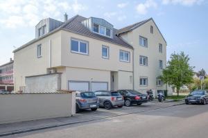 a large white house with cars parked in front of it at Pension Torkel-Stube in Ingolstadt