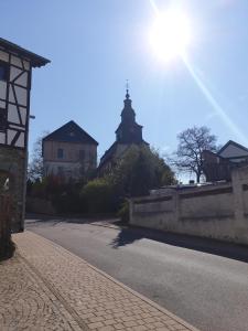 Blick auf eine Straße mit einer Kirche im Hintergrund in der Unterkunft Pension Zum Adler in Limbach