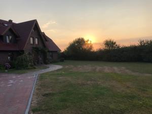 a house with the sunset in the background at Hillrichshof in Neuharlingersiel