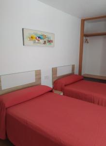 two beds in a room with red sheets at Hostal Rosa in Villajoyosa