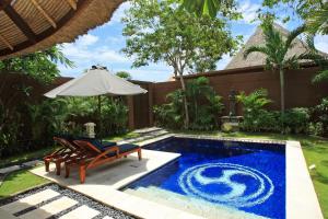 a swimming pool with two chairs and an umbrella at The Dusun in Seminyak