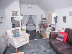 a living room with a couch and a kitchen at Pew with a View - Seafront Cottages in Sandhaven