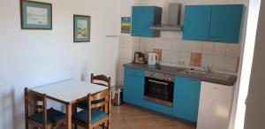 a small kitchen with blue cabinets and a small table at Apartment Roglić in Rab