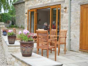 a patio with chairs and a table with flowers at The Plough Inn in Cheltenham