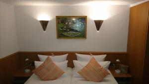 ein Schlafzimmer mit einem Bett mit Kissen und einem Bild an der Wand in der Unterkunft Pension Landhaus Fischer in Maßweiler