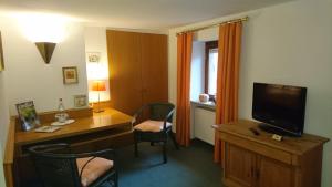 a room with a desk with a television and a desk with chairs at Pension Landhaus Fischer in Maßweiler