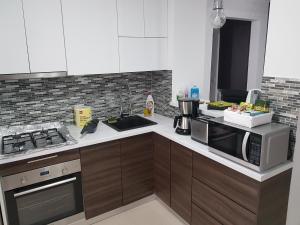 a kitchen with a sink and a stove and a microwave at Seaside Home Apartment in Mangalia