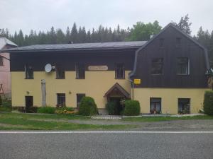 une maison noire et jaune avec un toit noir dans l'établissement Penzion Borovice, à Josefův Důl