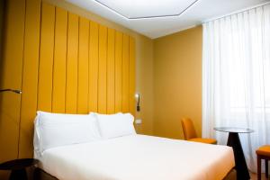 sypialnia z białym łóżkiem i żółtą ścianą w obiekcie Boutique Centrale Palace Hotel w Rzymie
