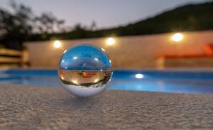 een glazen bal bovenop een tafel naast een zwembad bij Eden Mediterranean House in Vrsine