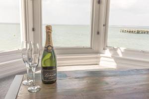 a bottle of champagne and two wine glasses on a table at Pier View Apartment in Totland
