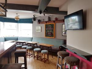 a restaurant with tables and stools and a flat screen tv at The Railway in Skipton