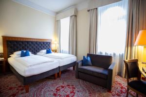 a hotel room with a bed and a chair at Hotel Kaiserhof Wien in Vienna
