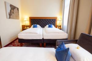 a hotel room with two beds with blue pillows at Hotel Kaiserhof Wien in Vienna