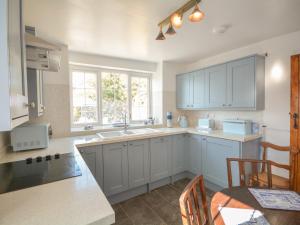 a kitchen with white cabinets and a table and a sink at Ffrwd in Holyhead