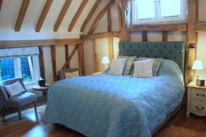 a bedroom with a blue bed and a chair at The Red Cow in Heydon