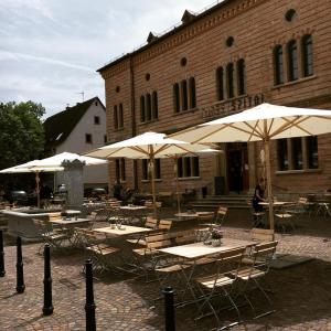 eine Gruppe von Tischen mit Sonnenschirmen vor einem Gebäude in der Unterkunft OX Hotel Altes Spital in Müllheim