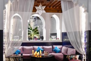 divano viola in camera con tende bianche di Riad Sheba a Marrakech
