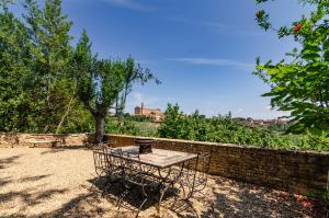 西恩納的住宿－Il giardino di Pantaneto Residenza D'Epoca，砖墙旁的院子内的桌椅