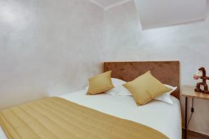 una camera da letto con un letto bianco con cuscini gialli di Roissy Appartements a Roissy en France