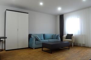 - un salon avec un canapé bleu et une chaise dans l'établissement Rosbacher nun Residenz, à Rosbach vor der Höhe