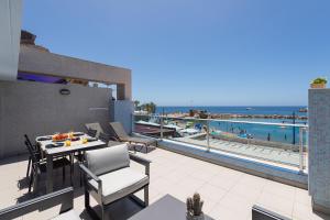 a balcony with a table and chairs and a view of the ocean at Amarre Bay in Puerto de Mogán