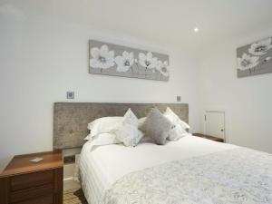 a bedroom with a white bed with two pictures on the wall at The Rose and Crown in Thorpe le Soken