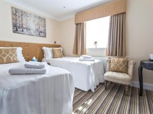 een hotelkamer met 2 bedden en een stoel bij The Rose and Crown in Thorpe le Soken
