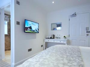 a bedroom with a bed and a tv on the wall at The Rose and Crown in Thorpe le Soken