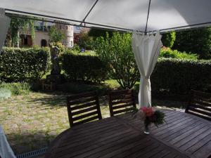 una mesa de madera con un paraguas blanco y flores. en Manoir du Rouvre, en Mettray