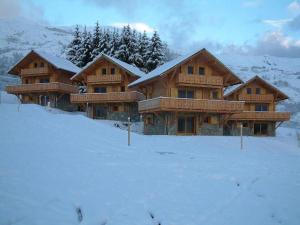 un par de casas de troncos en la nieve en Résidence Sourires et Vacances, en Saint-Pancrace