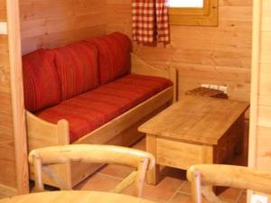 Cette petite chambre comprend un canapé rouge et une table. dans l'établissement Résidence Sourires et Vacances, à Saint-Pancrace