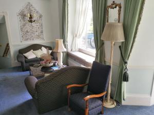 Rosemullion Hotel في فالموث: غرفة معيشة مع كرسيين وأريكة ونافذة