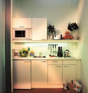 cocina con armarios blancos y microondas en Mondial Appartement Hotel, en Viena