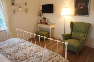 a living room with a couch and a chair and a television at Rosenhill B&B in Thalfang