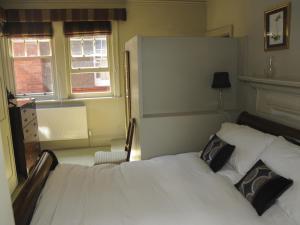 1 Schlafzimmer mit einem weißen Bett und 2 Fenstern in der Unterkunft Saffrons Apartment in Eastbourne + 13 Fotos