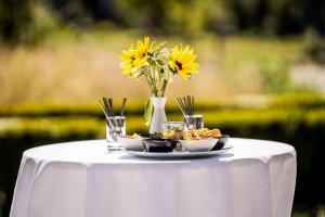 a white table with a plate of food and flowers at ODELYA - Stadthotel im Park in Basel