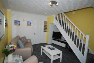 a living room with a couch and a staircase at Saltburn Holidays Jasmine Cottage Saltburn in Saltburn-by-the-Sea