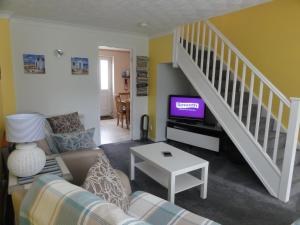 a living room with a couch and a tv at Saltburn Holidays Jasmine Cottage Saltburn in Saltburn-by-the-Sea