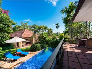 a view of a swimming pool with chairs and an umbrella at Samui Secret Villas in Choeng Mon Beach