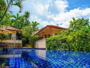a villa with a swimming pool in front of a house at Samui Secret Villas in Choeng Mon Beach