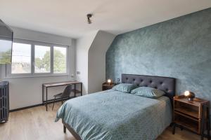 a bedroom with a bed with a blue accent wall at Le MoZen - Appartement proche hippodrome - St Malo in Saint Malo