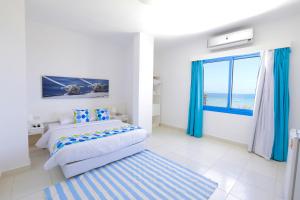 a white bedroom with a bed and a window at Lagoonie Lodge & Beach in Hurghada