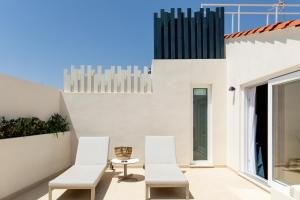 a patio with two white chairs and a table at Room Mate Collection Helen Berger in Valencia